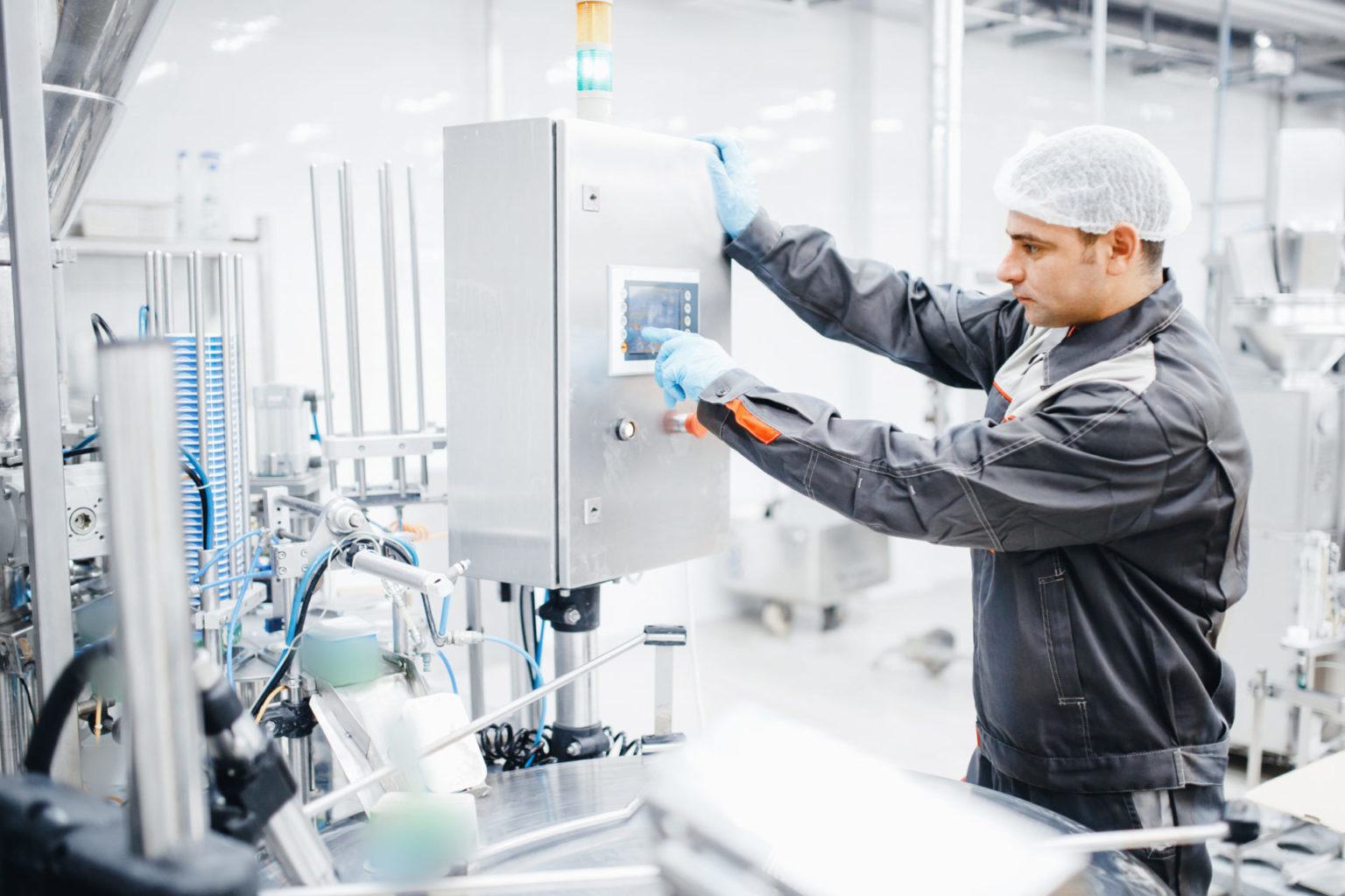 Male operator engineer controls production line from control panel, food factory.