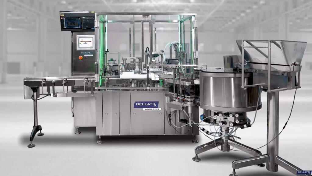 BellatRx Aquarius monobloc machine with a touchscreen, overhead monitor and a cap feeder bowl on a stand